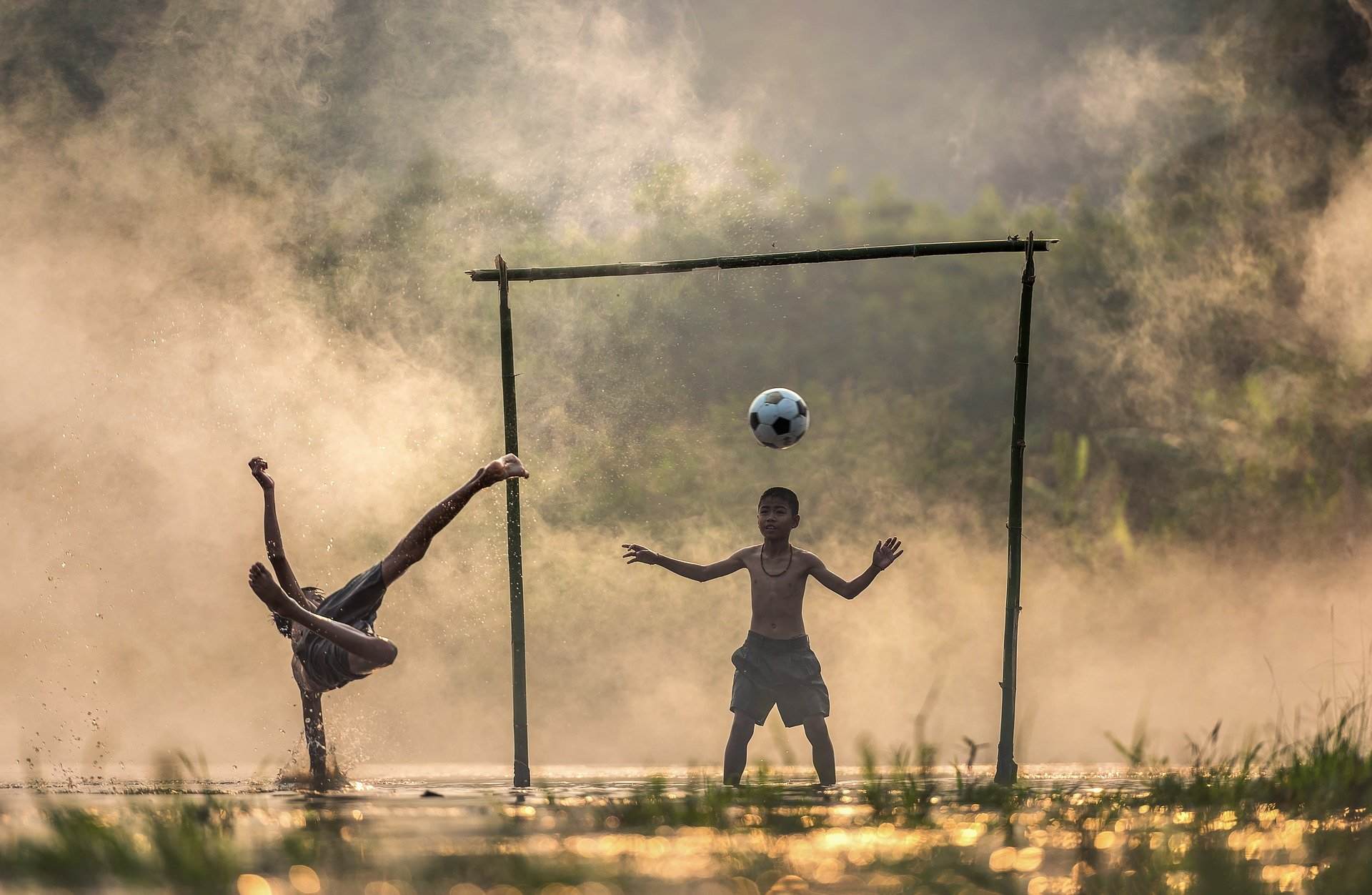 Zwei Kinder spielen im Nebel vor einem Fußballtor Fußball
